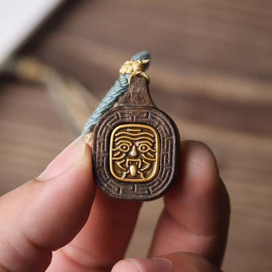 Close-up detail of Zhajilam wood carving and brass inset on Buddha amulet