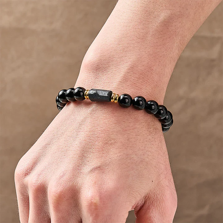 Close-up of monk blessed black tourmaline bracelet showing polished beads and raw crystal centerpiece