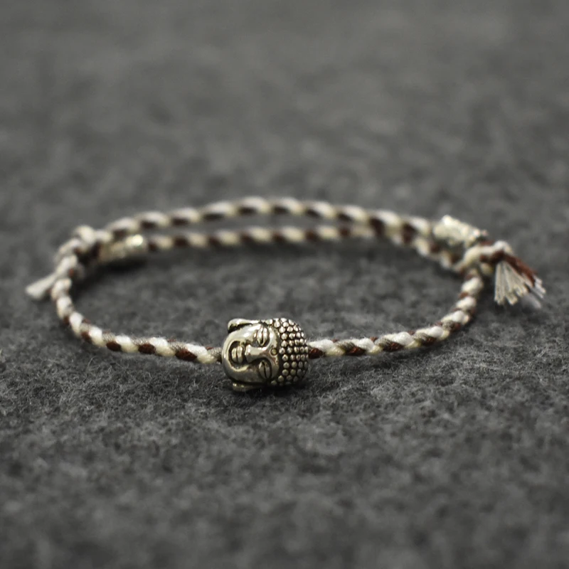 Braided wristband with patterned colors and silver Buddha charm on a dark surface