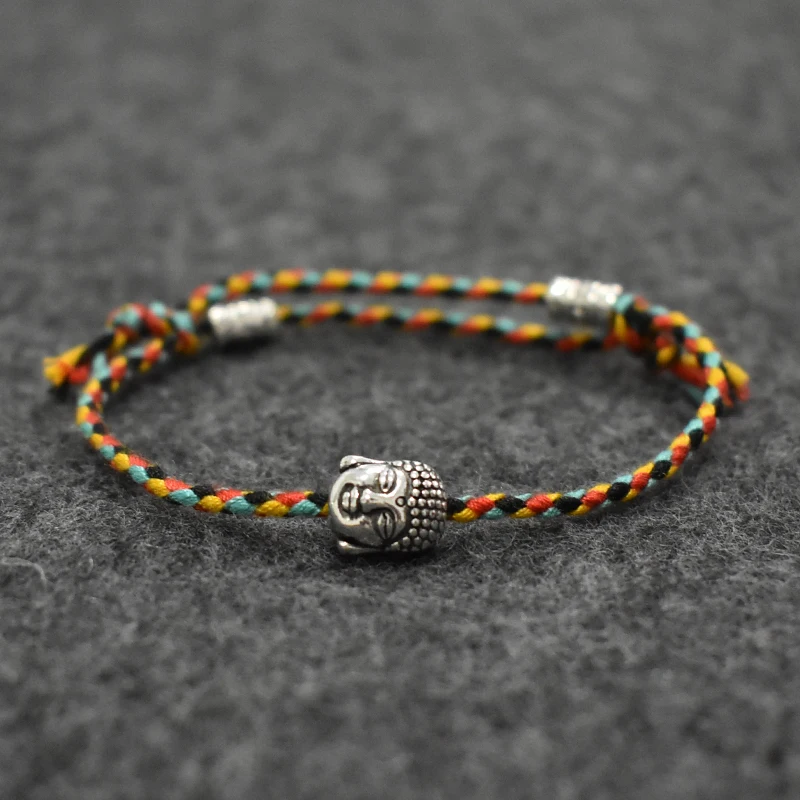 Vibrant, multi-colored braided bracelet with a detailed Buddha head accent on a textured background