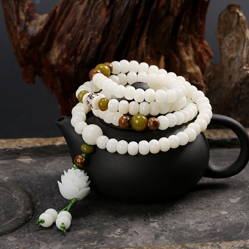 Elegant white bead bracelet with green and brown beads on a dark background