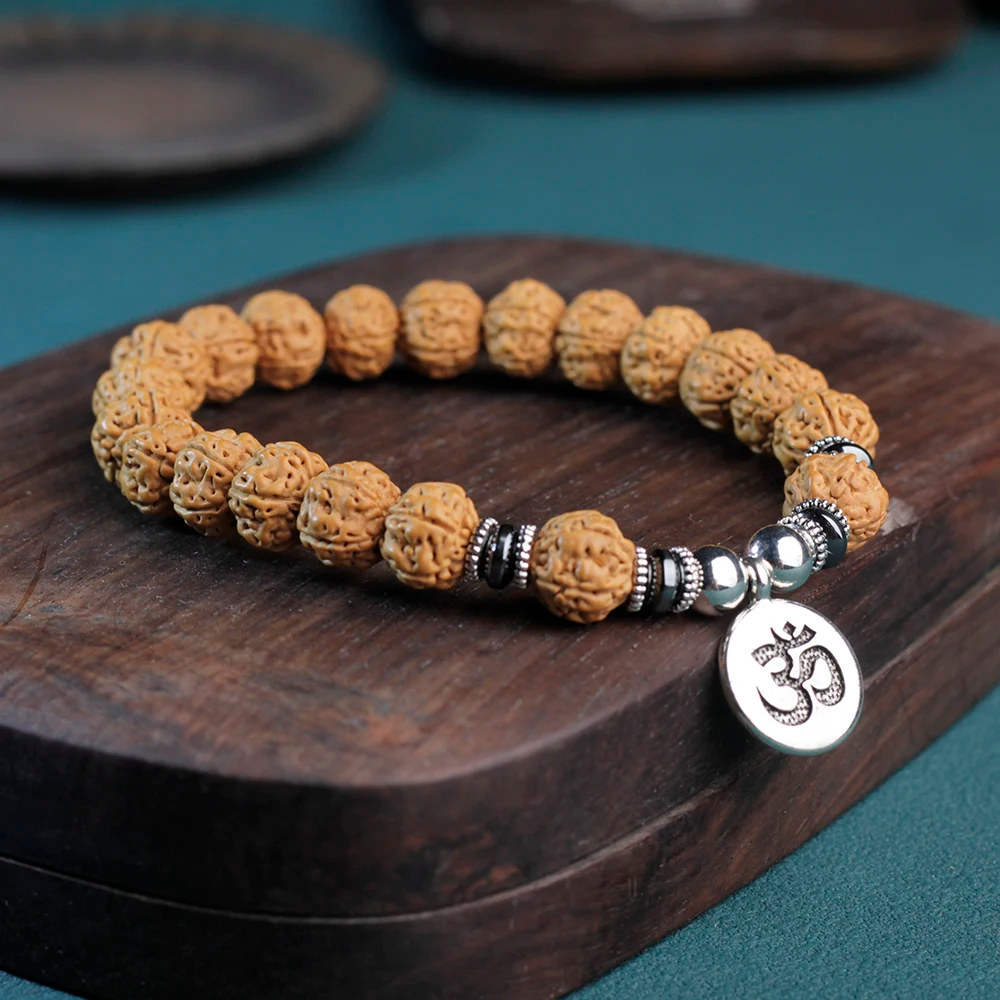 Stylish Rudraksha bracelet displayed on wooden surface, featuring a silver Om symbol