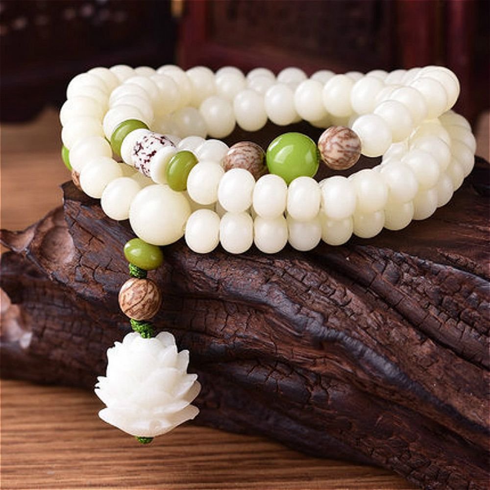 Intricate white beads and green accents on a wooden surface