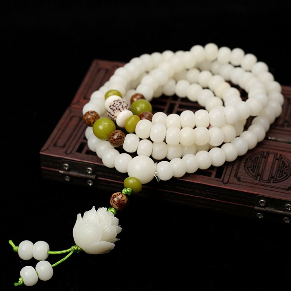 Intricately crafted white bead jewelry with green accents on a dark backdrop