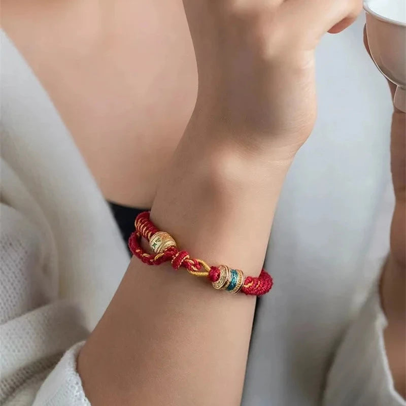 Red Tibetan Ethnic Hand-woven Rope Bracelet worn with white clothing and gold accents