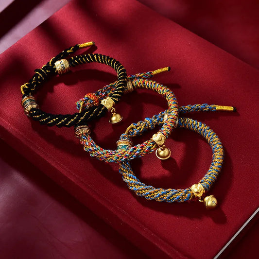 Tibetan Hand-woven Lucky Rope Bracelet trio with golden bells on red velvet display