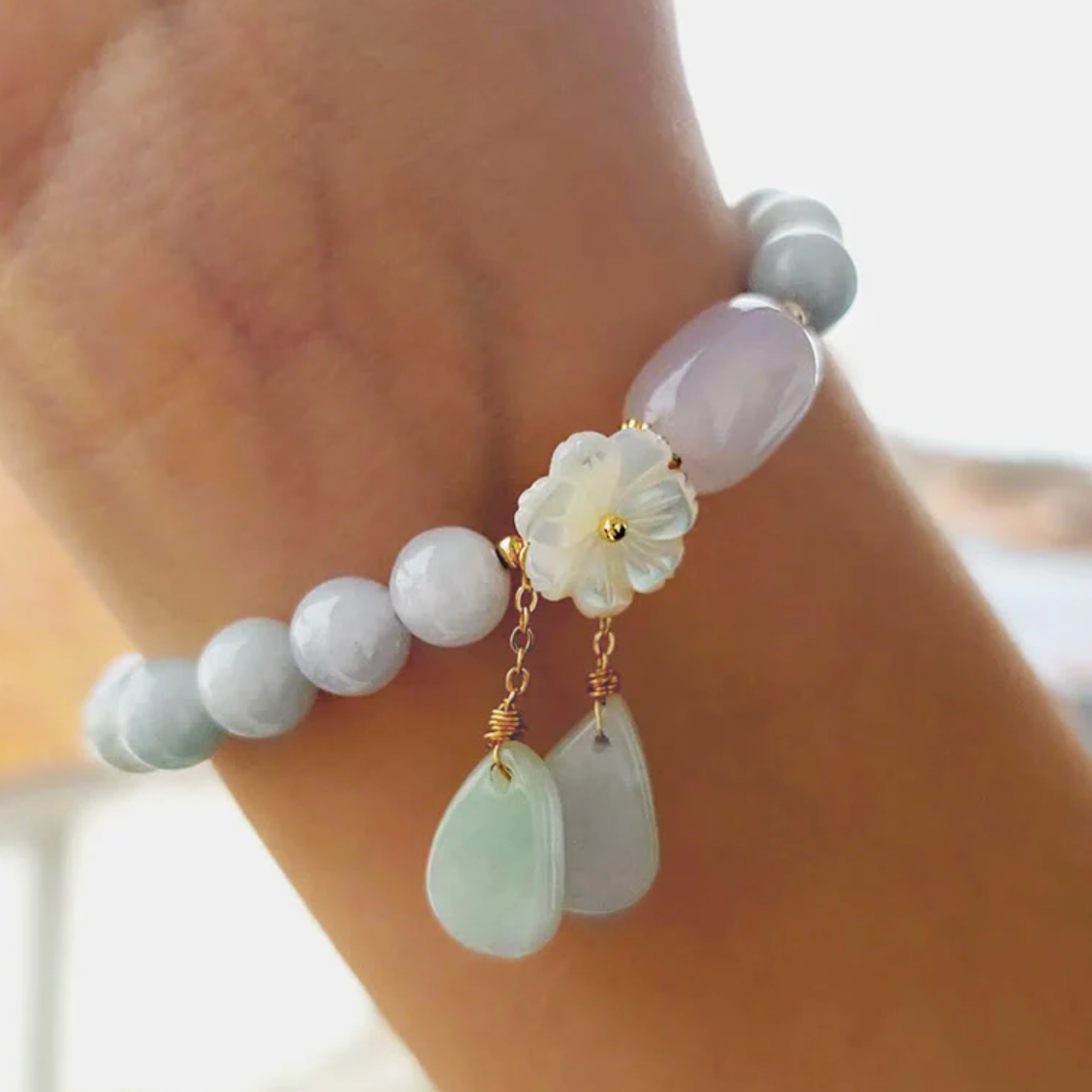 Elegant white jade bead bracelet with delicate flower charm and hanging stone accents, thoughtfully designed nature-inspired jewelry