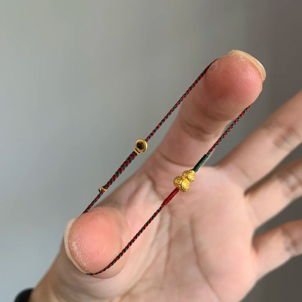 Close-up of the hammered gold gourd charm on braided cord bracelet