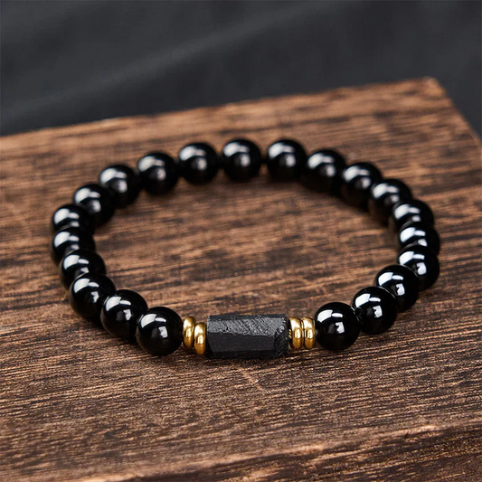 Black Tourmaline Protection Bracelet with raw center stone and gold spacers on natural wood background