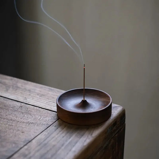 Handcrafted black walnut incense holder resting in palm, showing smooth wood grain