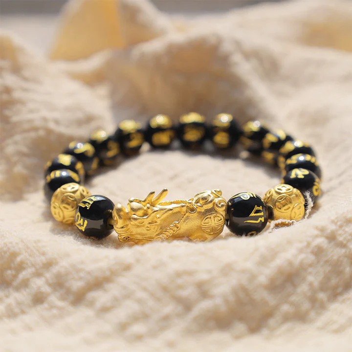 A black obsidian Pixiu bracelet resting on a stone surface under natural moonlight for spiritual cleansing