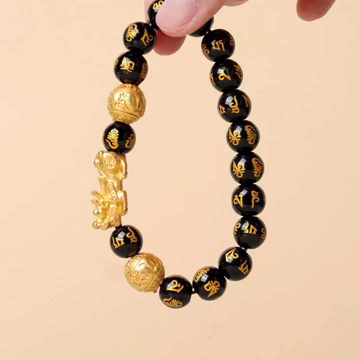 A Feng Shui black obsidian bracelet with a gold Pixiu charm isolated on a clean background
