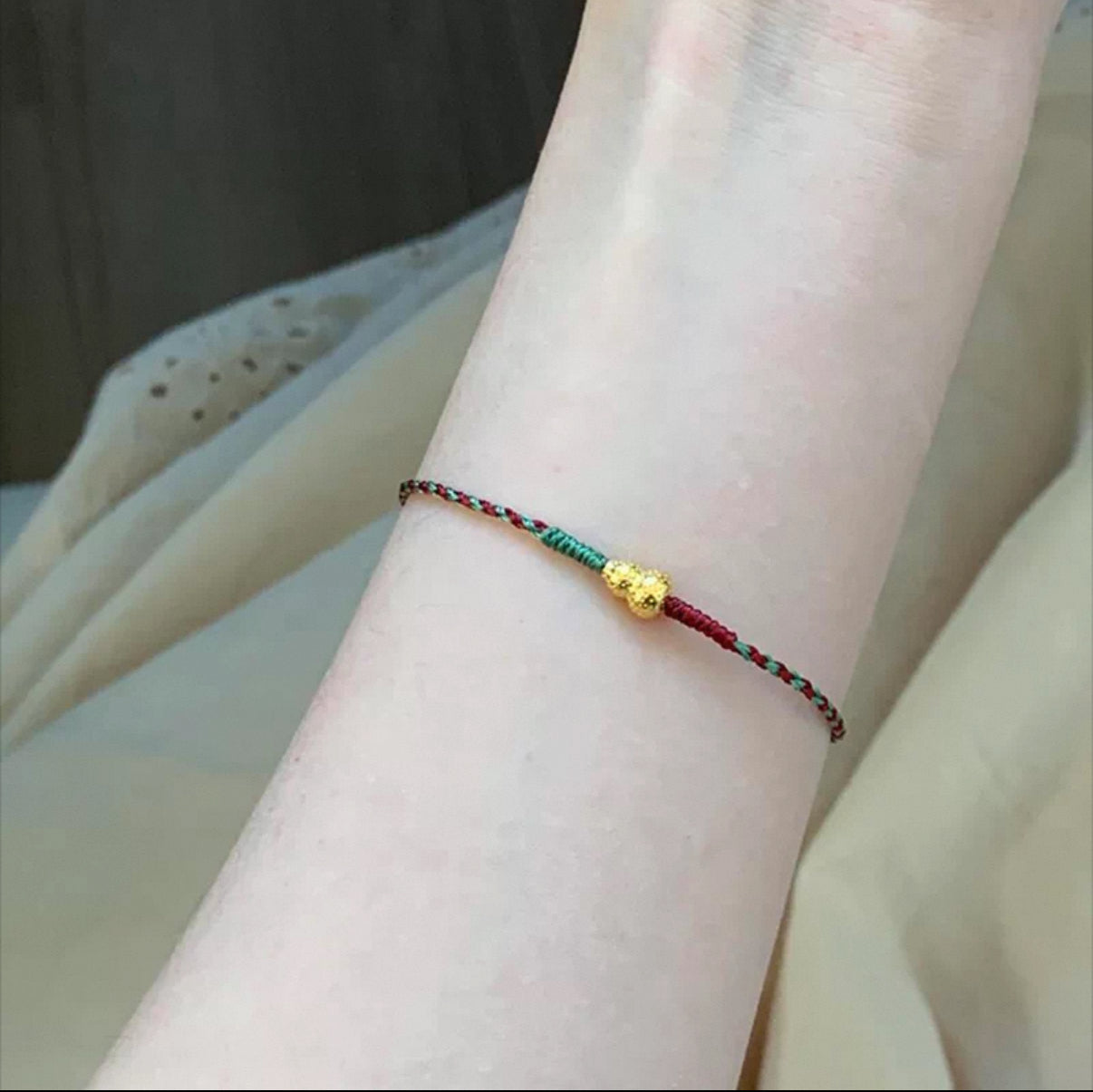 Hand-woven red and green cord bracelet with gold charm for daily wear