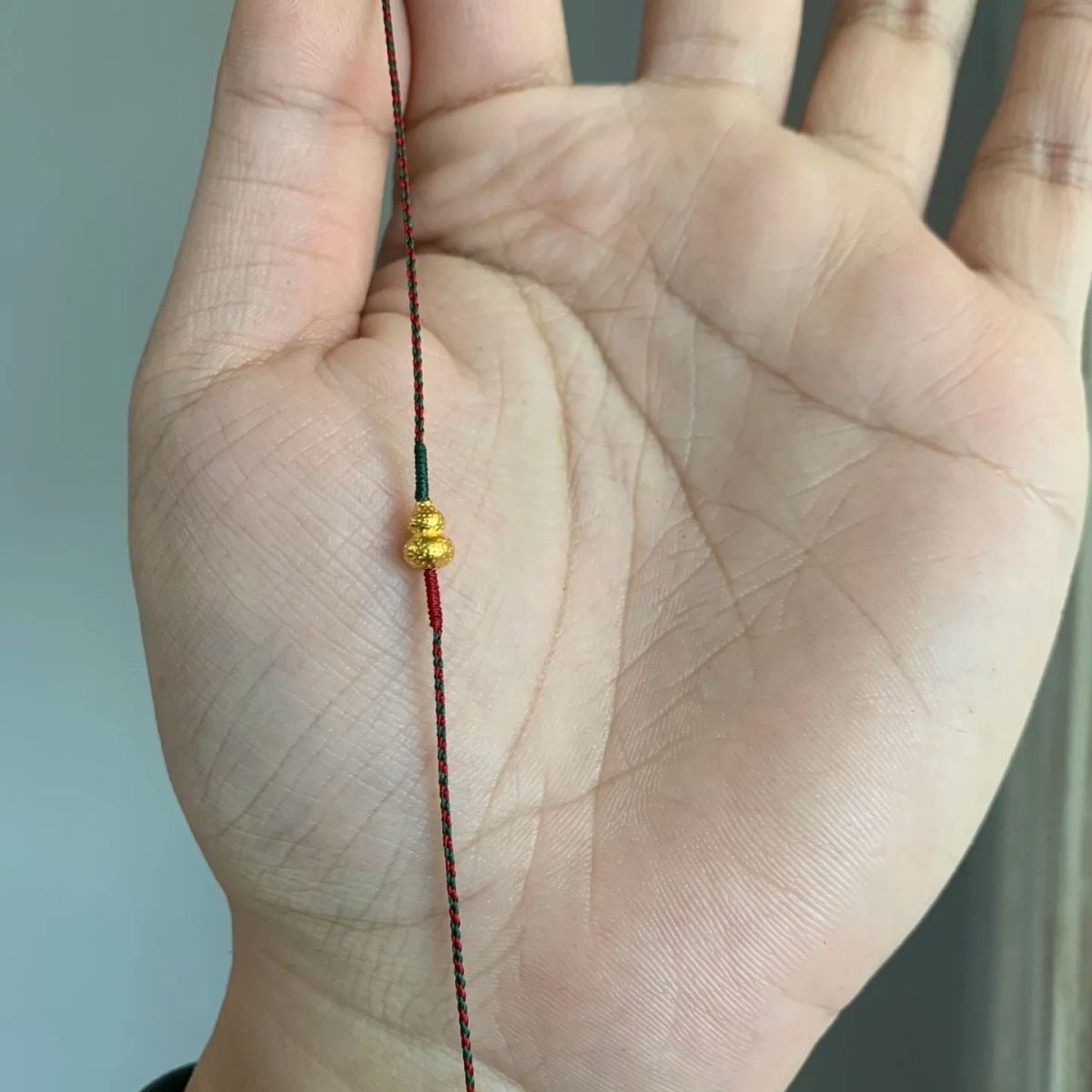 Red and green braided bracelet with gold-plated hammered gourd pendant