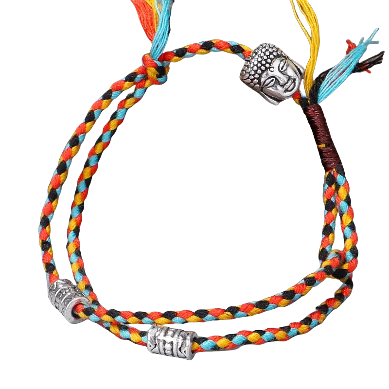 Intricate, colorful braided bracelet with decorative Buddha head charm against a dark background