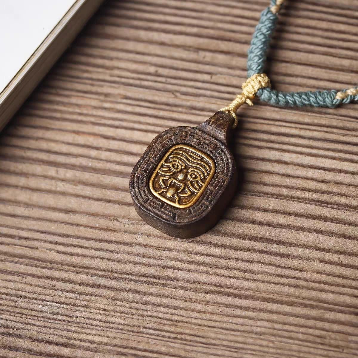 Front view of Zashi Lhamo wood-carved Buddha amulet pendant on braided cord