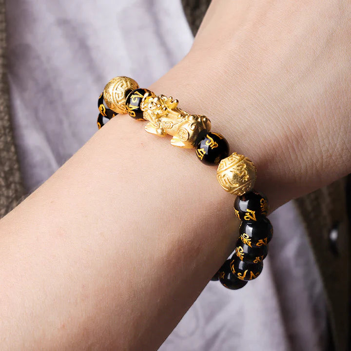 A close-up of a person wearing a black obsidian Pixiu wealth bracelet on their left wrist for good luck