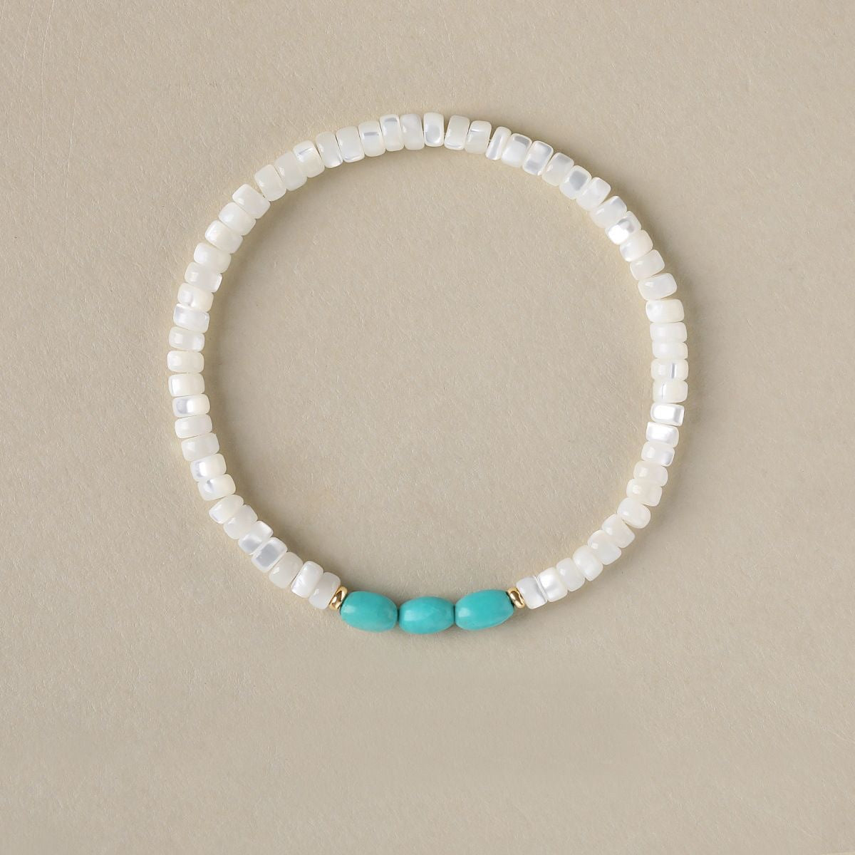 White shell bracelet with turquoise rice bead accent.